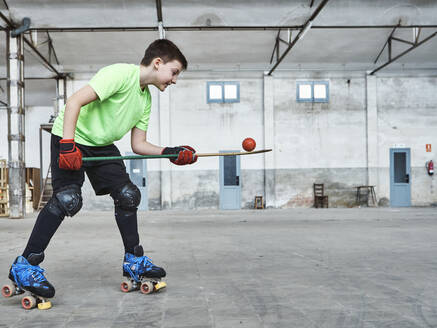 Boy balancing ball on hockey stick during training at court - VEGF02833