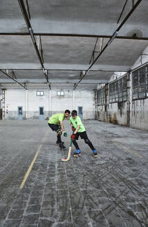 Father teaching son playing roller hockey on court - VEGF02841