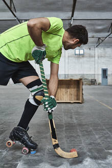 Mature male athlete practicing roller hockey while aiming at wooden box - VEGF02847