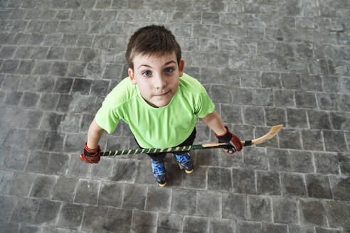 Boy holding hockey stick while standing at court - VEGF02852