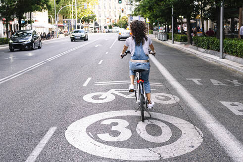 Ältere Frau fährt auf dem Fahrradweg in der Stadt - JCMF01204