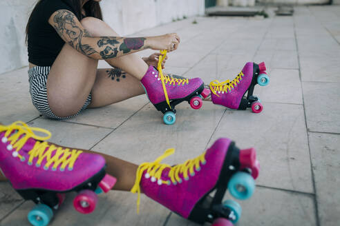 Low Section of friends with roller skates sitting on footpath - DCRF00701