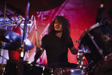 Concert of drummer playing drum kit while performing on stage in live event - SAJF00075