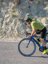 Gesunder Mann auf dem Fahrrad auf einer Bergstraße an einem sonnigen Tag - ADSF12135