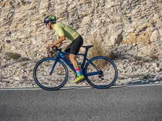 Gesunder Mann auf dem Fahrrad auf einer Bergstraße an einem sonnigen Tag - ADSF12136