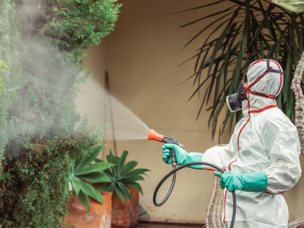 Räuchermaschine in weißer Uniform, die eine Substanz im Garten versprüht - ADSF12140