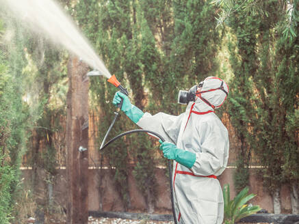 Räuchermaschine in weißer Uniform, die eine Substanz im Garten versprüht - ADSF12142