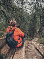 Wanderin, die sich ausruht und ihr Smartphone benutzt, während sie in einer malerischen Gegend in den Dolomiten, Italien, sitzt - ADSF12152