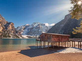 Beautiful landscape with wooden stilt house on breathtaking lake surrounded with rocky snowy mountains - ADSF12212