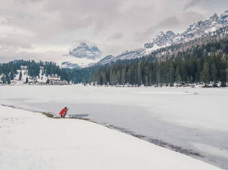 Unbekannte Person steht im Schnee, umgeben von Wald und Bergen - ADSF12215