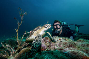 Freitaucher schwimmt unter Wasser mit großer Schildkröte im Ozean - ADSF12228