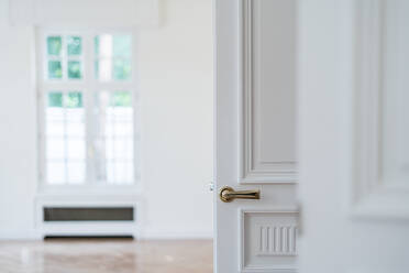 Offene weiße Tür mit goldenen Griff in hellen minimalistischen Interieur auf unscharfen Hintergrund - ADSF12241