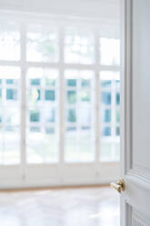 Offene weiße Tür mit goldenen Griff in hellen minimalistischen Interieur auf unscharfen Hintergrund - ADSF12242