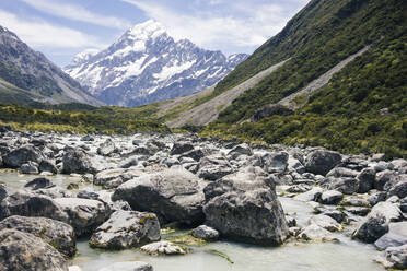 Rocky Fluss zwischen grünen Klippen mit Berg Cook und Himmel auf Hintergrund in Neuseeland - ADSF12250
