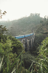 Von oben blauer Zug auf Steinbrücke im tropischen grünen Dschungel bei nebligem Wetter in Sri Lanka Asien - ADSF12290