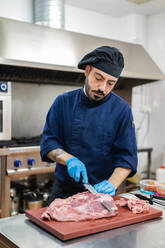 Koch schneidet Fleisch in der Küche - ADSF12306