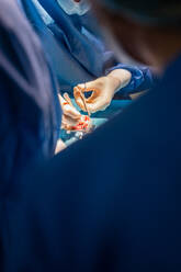 Veterinärchirurgen und Krankenschwestern in Uniform, die sich auf die Operation eines Hundes konzentrieren und spezielle Geräte im Operationssaal eines modernen Krankenhauses verwenden - ADSF12359