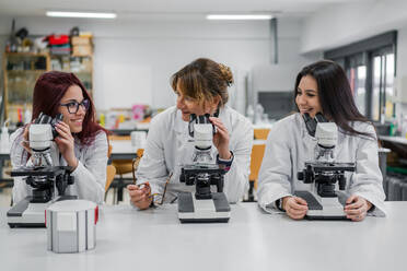 Female scientists using microscopes in lab - ADSF12417
