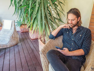 Trendiger gut aussehender Mann mit Telefon auf der Terrasse - ADSF12449