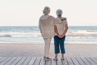 Rückenansicht friedlich reifen weißhaarigen Freundinnen umarmt am Strand und Blick auf das Meer im Sommer Tag, während die Erinnerung an alte Zeiten - ADSF12470