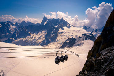 Von oben überdachte Hütten, die mit der Seilbahn in den weiß verschneiten Bergen an einem wolkenverhangenen Tag in Chamonix, Mont-Blanc, hinunterfahren - ADSF12513