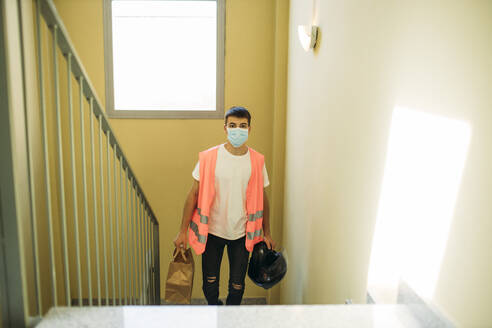 Delivery man with a mask during the new reality going upstairs - GMLF00504