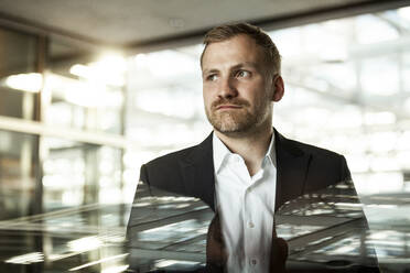 Portrait of businessman looking sideways in office building - SAJF00081