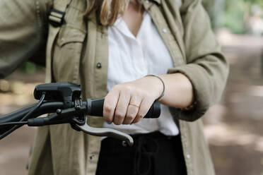Junge Frau hält Lenker eines Elektrofahrrads - RDGF00111