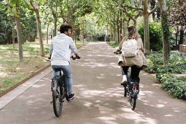 Young couple riding electric bicycles on road - RDGF00114