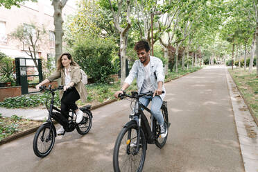Couple riding electric bicycles on road - RDGF00116