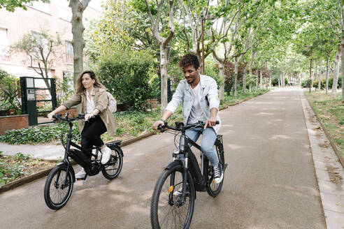 Ehepaar fährt mit Elektrofahrrädern auf der Straße - RDGF00116