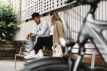 Young couple talking while sitting on bench - RDGF00123