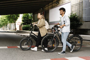 Ehepaar überquert Straße mit Elektrofahrrädern in der Stadt - RDGF00125