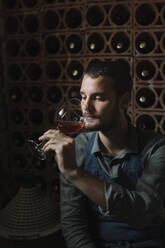 Young man looking at wine in glass during tasting - ALBF01418