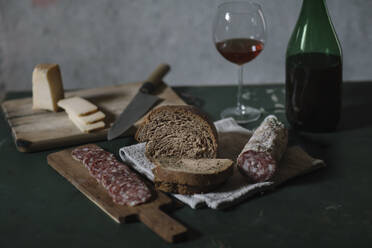 Close-up of fresh salami sausage with homemade bread and wine on table in cellar - ALBF01422