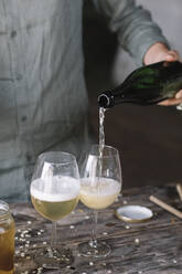 Mittelteil eines Mannes, der bei der Zubereitung eines Cocktails Wein in ein Glas gießt - ALBF01450
