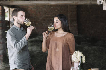 Couple drinking cocktail standing at barn - ALBF01459