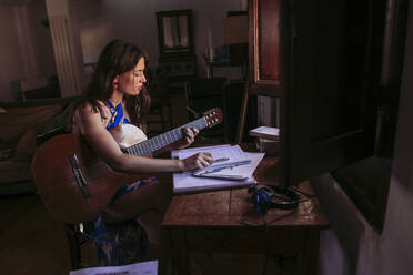 Junge Frau übt Gitarre zu Hause - LJF01767