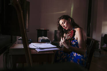 Young woman practicing guitar at table in living room - LJF01774