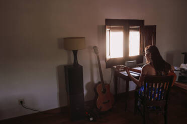 Young woman practicing guitar in living room at home - LJF01776