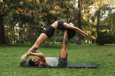 Boyfriend lifting girlfriend while practicing acroyoga in park - MRRF00350