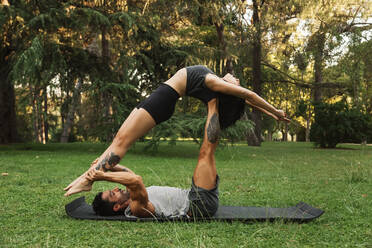 Freund hebt Freundin beim Üben von Acroyoga im Park - MRRF00350