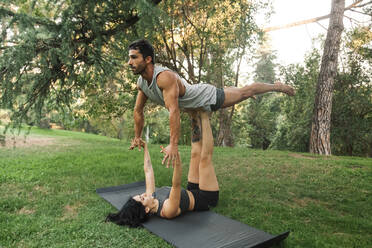 Male and female athletes practicing acroyoga in public park - MRRF00354