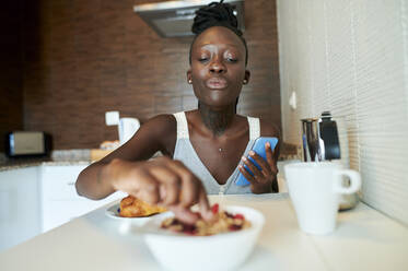 Junge Frau beim Frühstück in der Küche zu Hause - KIJF03230