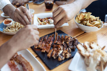 Hands of friends enjoying fresh meal at restaurant - JSRF01108