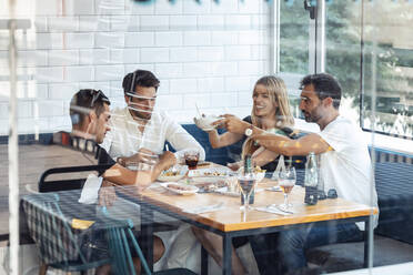 Freunde genießen eine Mahlzeit in einem Restaurant, gesehen durch ein Fenster - JSRF01109
