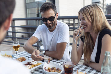 Lächelnde Freunde beim Essen in einem Restaurant - JSRF01111