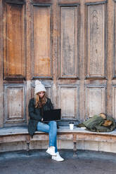 Geschäftsfrau sitzt auf einer Bank und benutzt einen Laptop im Park - JMPF00365