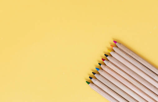 Colored pencils arranged on yellow background - MOMF00906