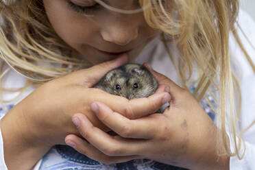 Nahaufnahme eines niedlichen Mädchens, das mit einem Hamster spielt - JFEF00968